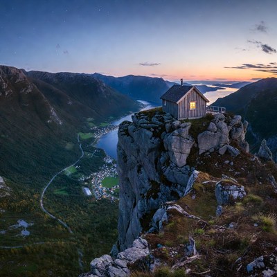 Cabin on Cliff Overlooking Lake at Sunset
