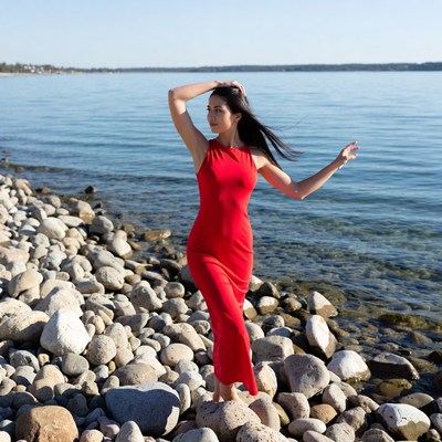 Woman in red dress on lakeside rocks
