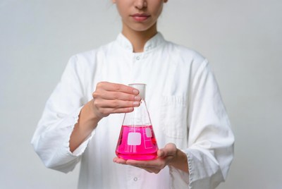 Woman holding pink flask in lab coat