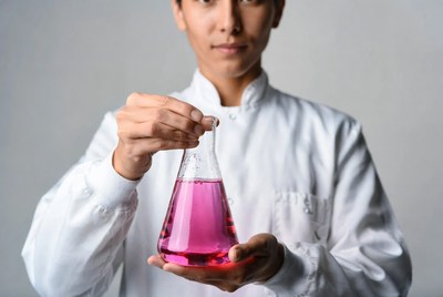 Asian scientist holding pink chemical flask