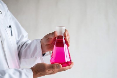 Man holding pink liquid Erlenmeyer flask