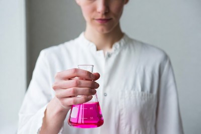 Woman holding pink liquid Erlenmeyer flask