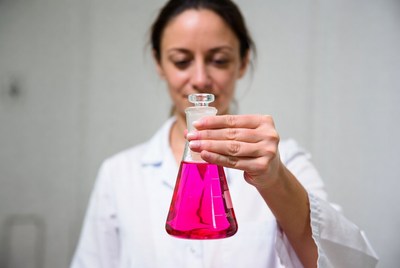Woman holding pink lab flask