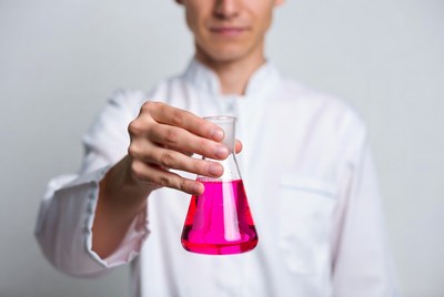 Man holding pink liquid Erlenmeyer flask