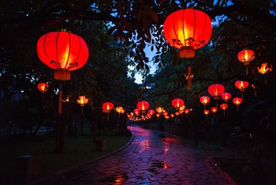 Red lanterns hanging over wet pathway