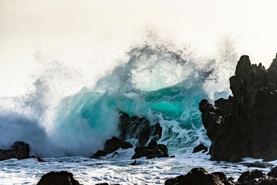 Massive turquoise wave crashing on rocks