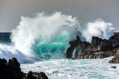 Massive turquoise waves crashing on rocks