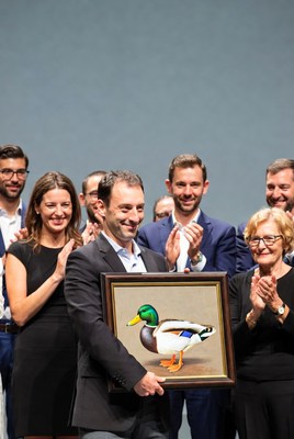 Man holding duck painting with group