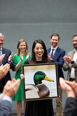 Asian woman holding duck photo with clapping group