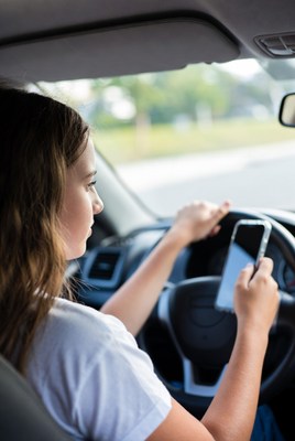 Young woman driving while using phone
