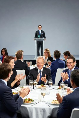 Man speaking at podium to clapping audience