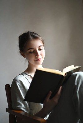 Young woman reading book in chair