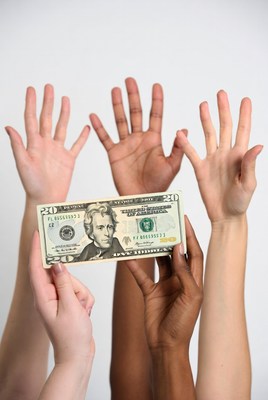 Diverse hands holding twenty dollar bill