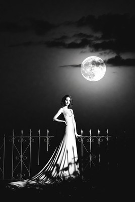 Woman in white gown on balcony under full moon