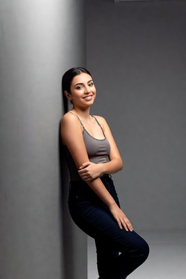Smiling woman leaning against gray pillar