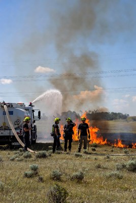Firefighters spraying water on grass fire