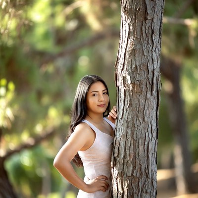 Latina woman leaning against tree
