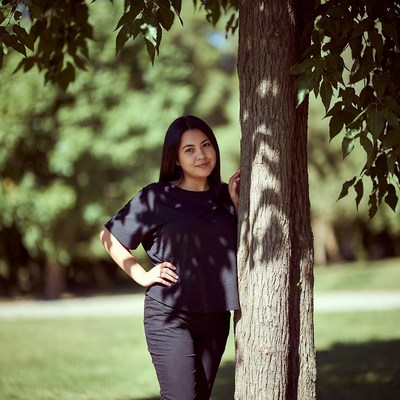 Asian woman leaning against tree