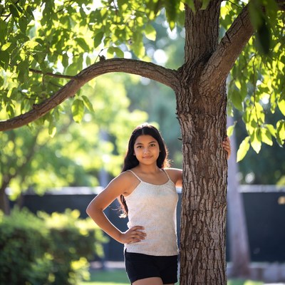 Latina girl leaning against tree