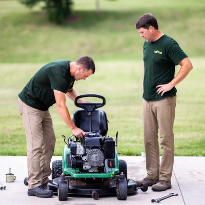 Two men repairing lawn mower