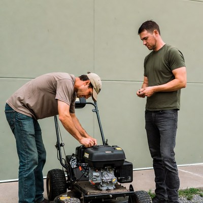 Two men repairing lawn mower
