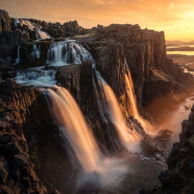 Waterfall cascading over basalt cliffs at sunset