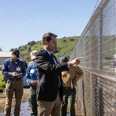 Man in suit pointing at chain-link fence