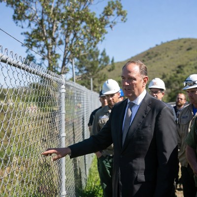 Man in suit pointing at chain-link fence