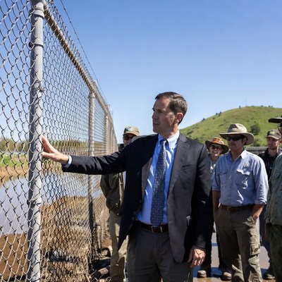 Man in suit pointing at chain-link fence