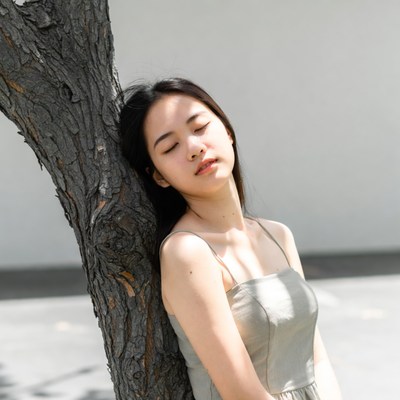 Asian woman leaning against tree