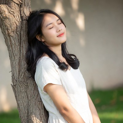 Asian girl leaning against tree
