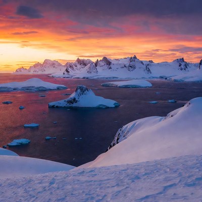 Arctic Sunset Over Snowy Mountains and Icebergs
