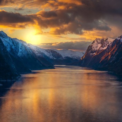 Sunset over snowy mountain fjord