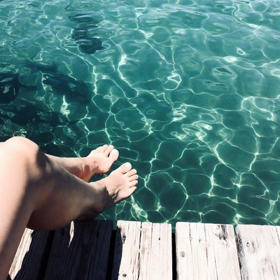 Woman's feet dangling over lake dock
