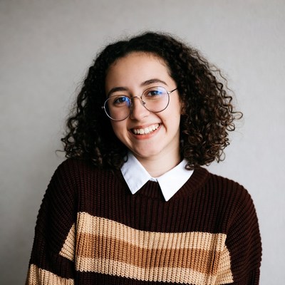 Smiling young woman with curly hair and glasses