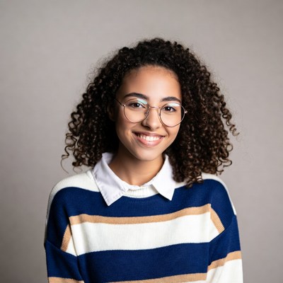 Smiling young woman with curly hair and glasses