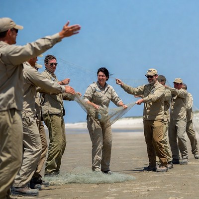 Group pulling fishing net on beach
