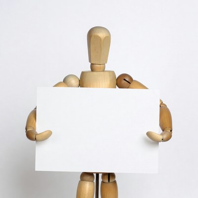 Wooden artist mannequin holding blank sign