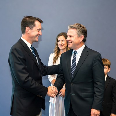Men shaking hands with woman and boy