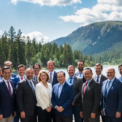 Business group standing by lake mountains