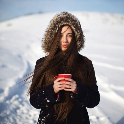 Woman holding red mug in snowy landscape