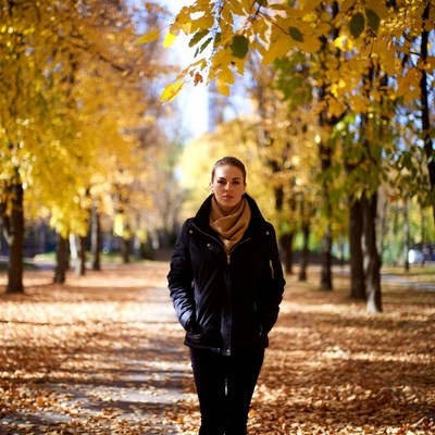 Woman walking autumn alley yellow trees