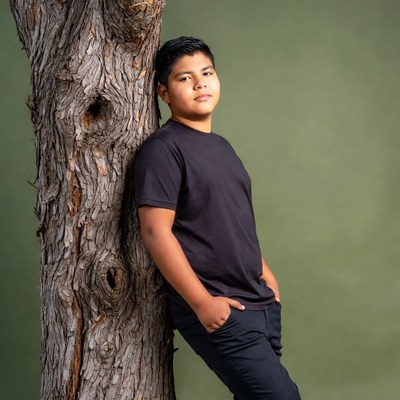 Latino boy leaning against tree
