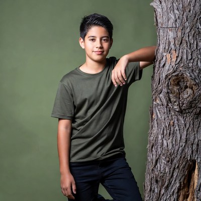 Latino boy leaning against tree