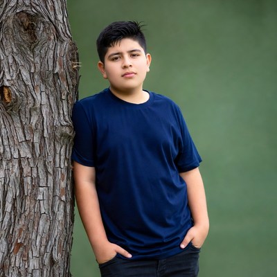 Latino boy leaning against tree