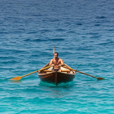 Man rowing wooden boat on sea