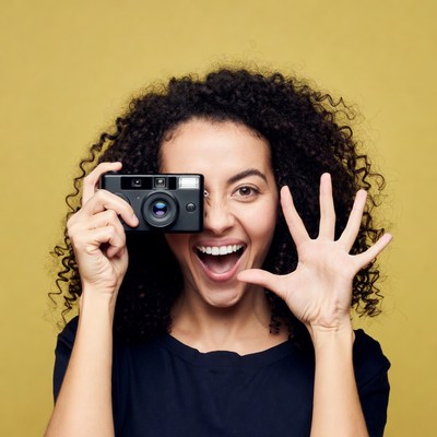 Happy woman holding camera peeking through