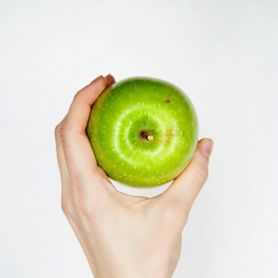 Woman's hand holding green apple