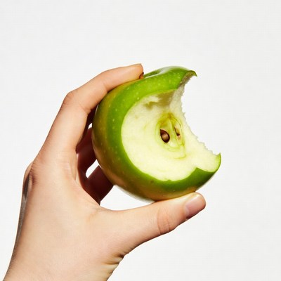 Hand holding bitten green apple