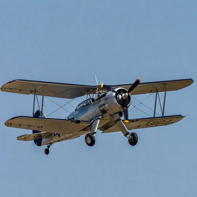 Silver biplane flying in blue sky